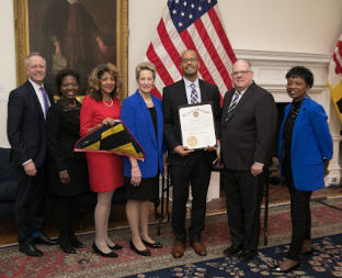 Maryland Governor Larry Hogan, State Superintendent of Schools Dr. Karen B. Salmon with 4 representatives from Clarksville Middle School holding a certificate and a Maryland flag.