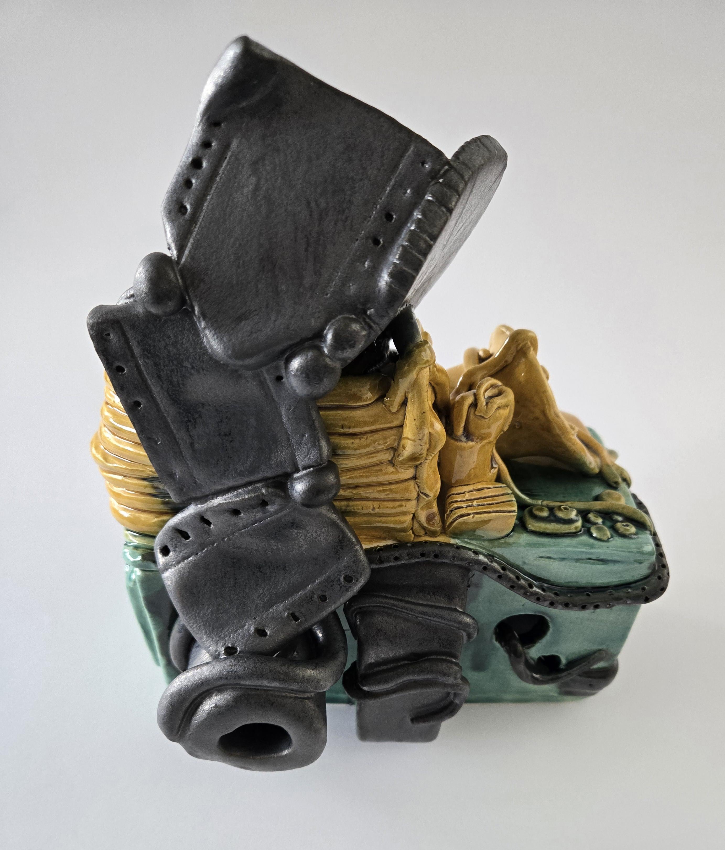 Clay sculpture of a vintage camera with film cascading over the camera body. Medium: clay.