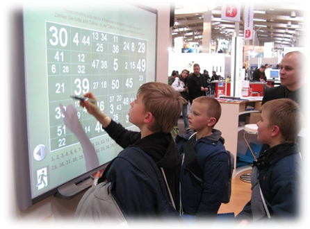 students and a teacher work on a math problem on an electronic smart board